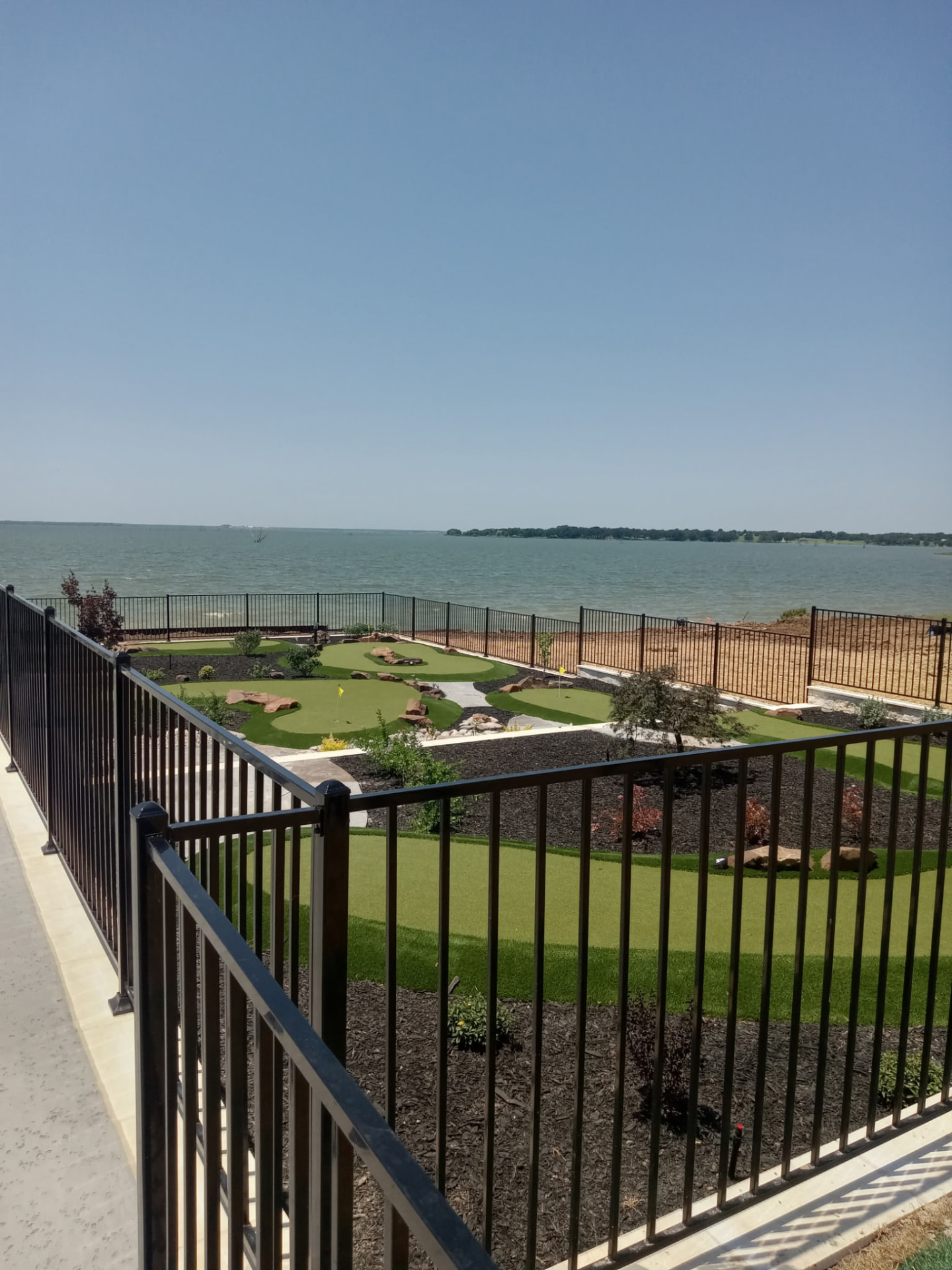 Black ornamental iron fence overlooking a lake, built by Martin's Fencing